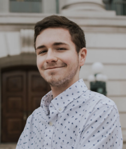 A man wearing a patterned shirt smiles. 